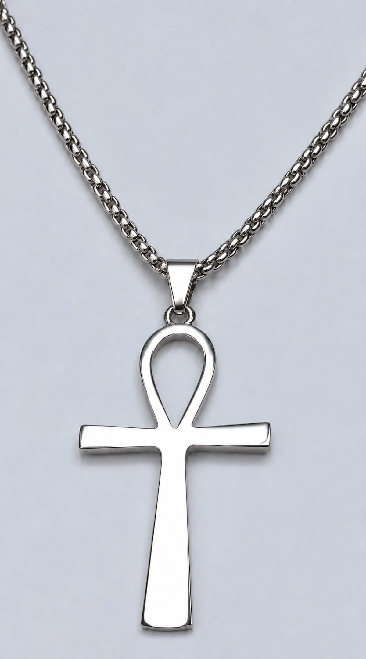 Cruz egipcia Ankh de acero inoxidable con cadena sobre fondo claro.