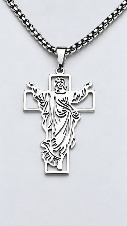Cruz con Jesús de acero inoxidable en acabado plateado y cadena sobre fondo claro.