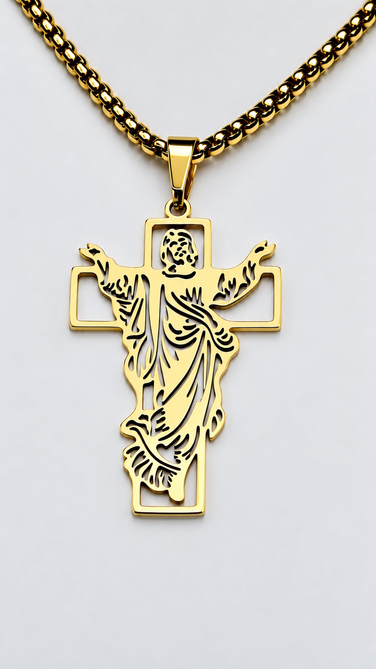 Cruz con Jesús de acero inoxidable en acabado dorado y cadena sobre fondo claro.