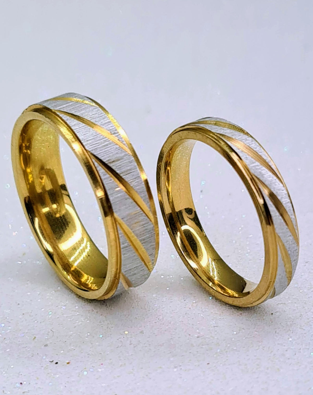 Set de dos alianzas bicolor de acero inoxidable de 4 y 6 mm con detalles diagonales dorados.