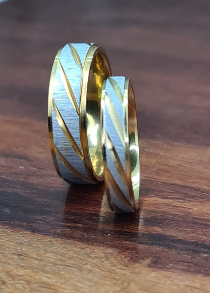 Alianzas de pareja bicolor de diferentes anchos colocadas sobre superficie de madera.