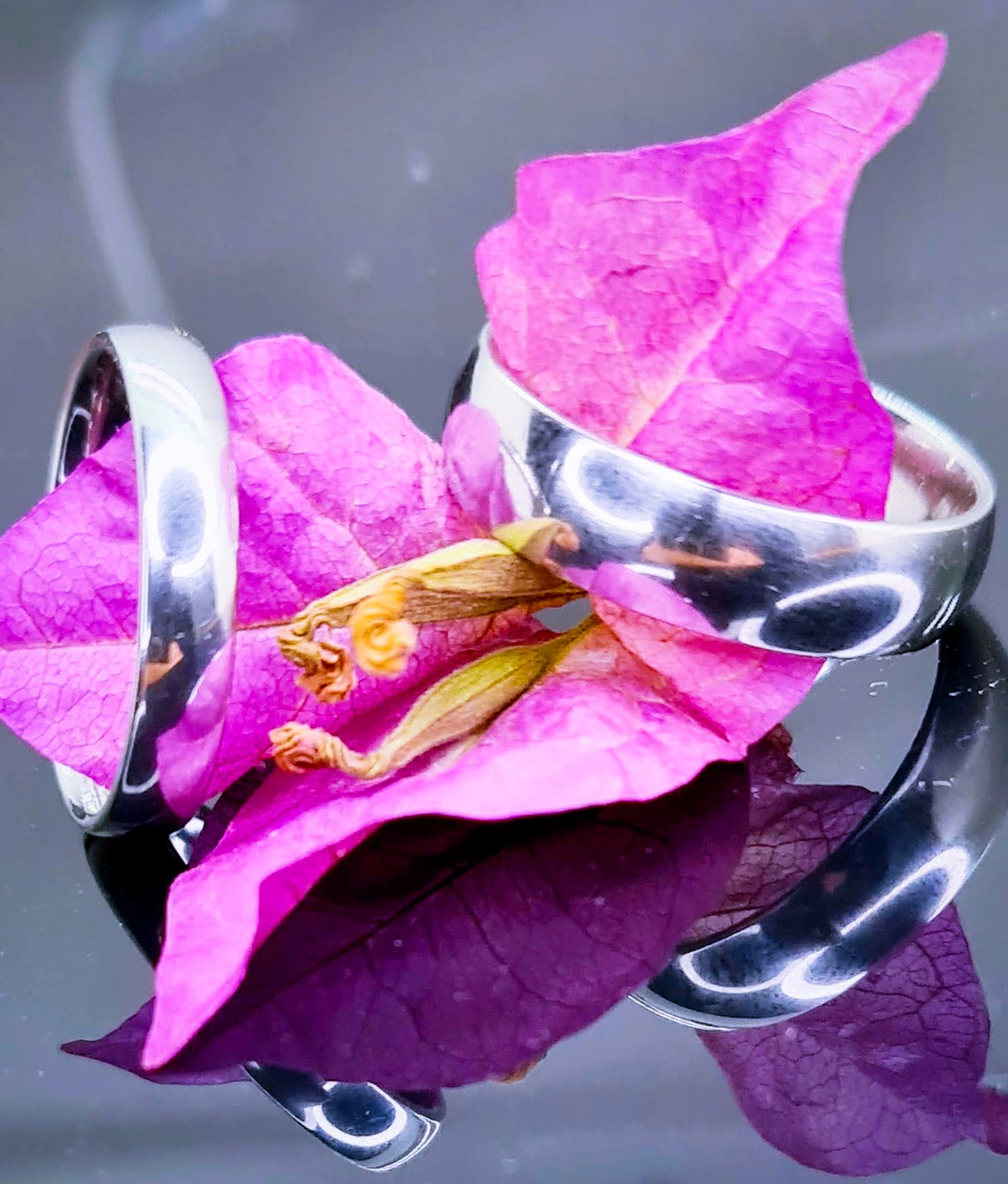 Dos Anillos tipo alianza de matrimonio o pareja en acero inoxidable media caña anchos de 4 y 6mm. Se incluye grabado de nombres y fecha importante gratis. Se posan sobre una flor.