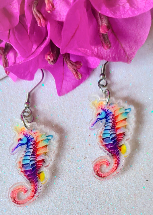 Pendientes Caballito de mar para mujer en Acero y Acrílico. Posa sobre fondo blanco y flores.