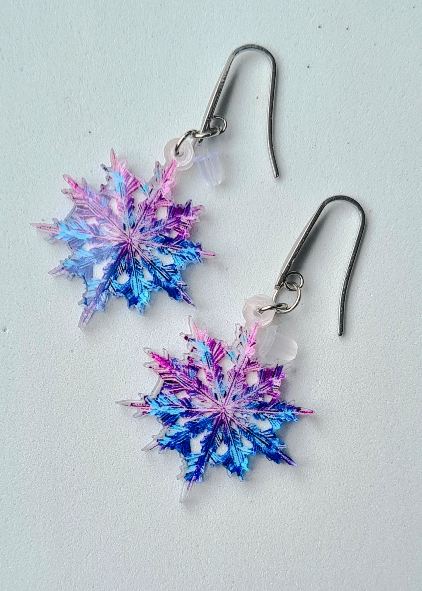 Pendientes Copo de Nieve para mujer en Acero y Acrílico. Posa sobre fondo blanco.