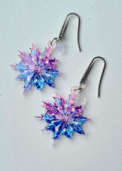 Pendientes Copo de Nieve para mujer en Acero y Acrílico. Posa sobre fondo blanco.