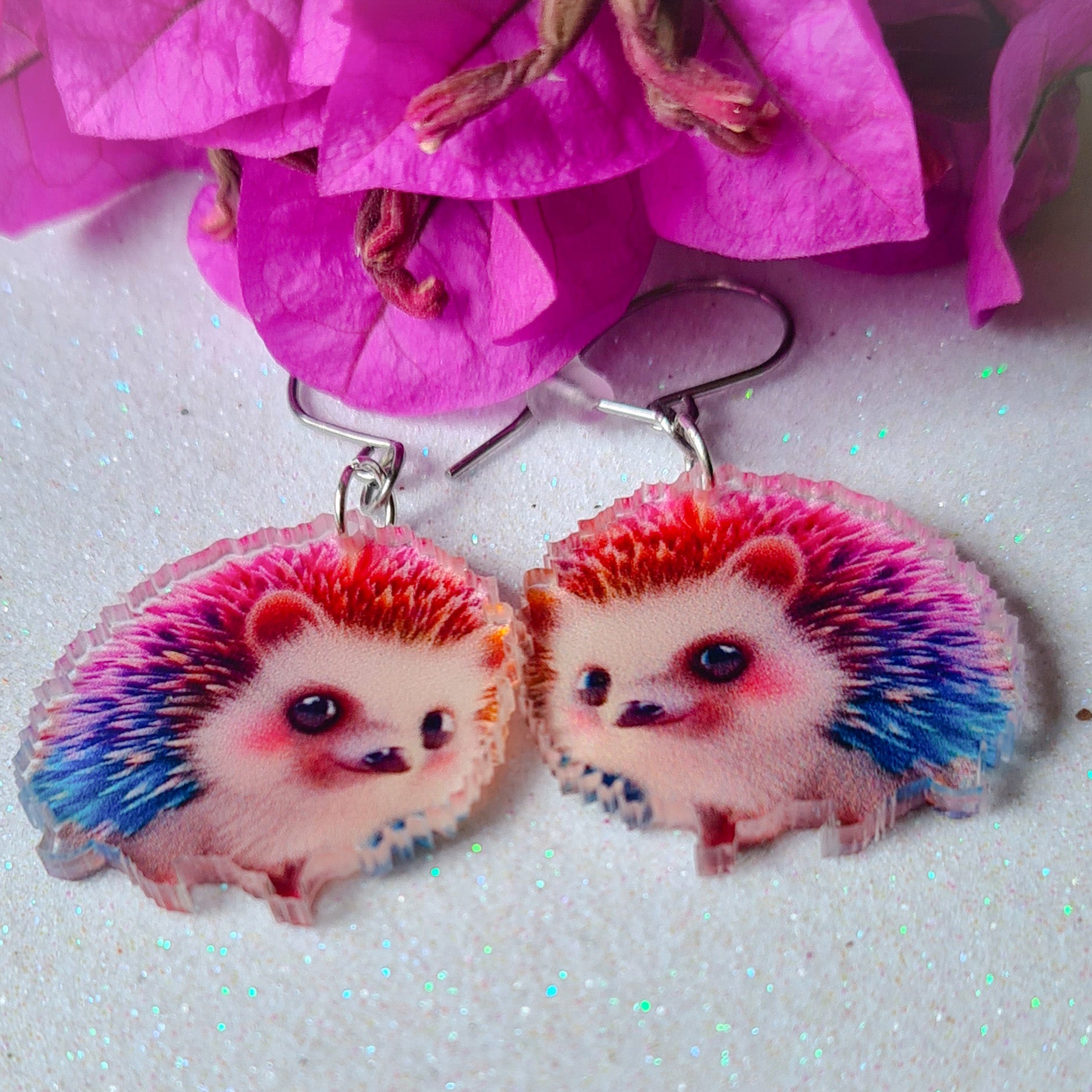 Pendientes Erizo para mujer en Acero y Acrílico. Posa sobre fondo blanco y flores.