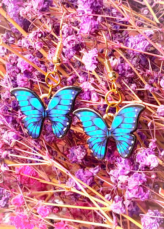 Pendientes Mariposa azul para mujer en Acero y Acrílico. Posa sobre ramas con flores.