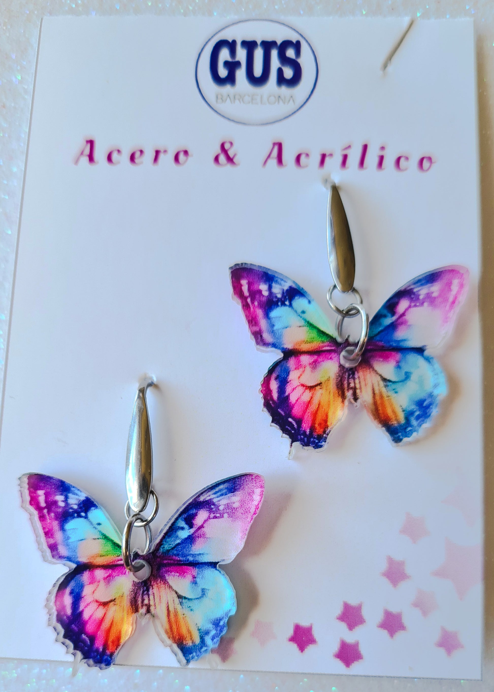 Pendientes Mariposa multicolor para mujer en Acero y Acrílico. Posa sobre cartón blanco.