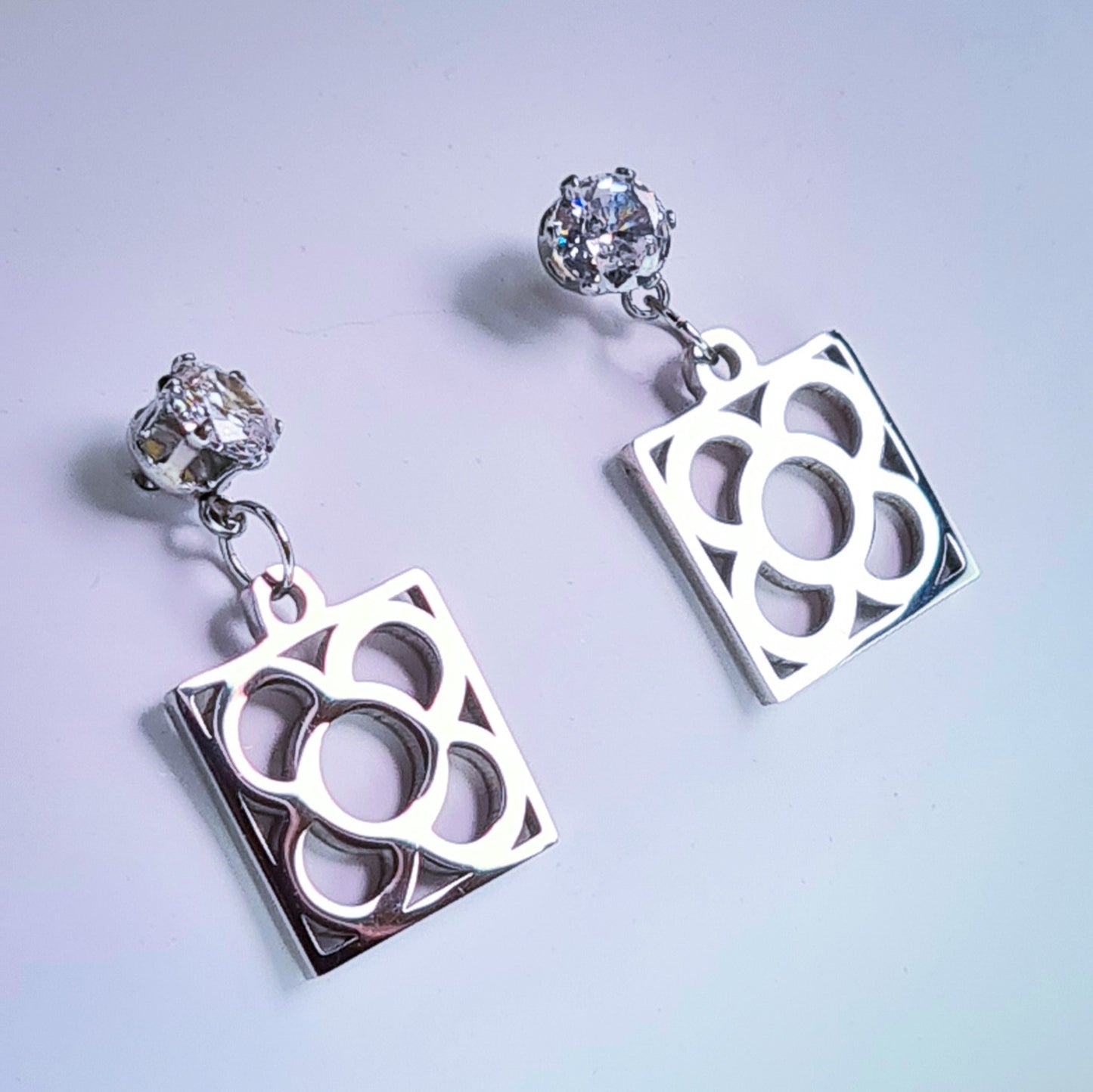 Pendientes de acero inoxidable plateado con tope de circonita blanca y la Flor de Barcelona para mujer.