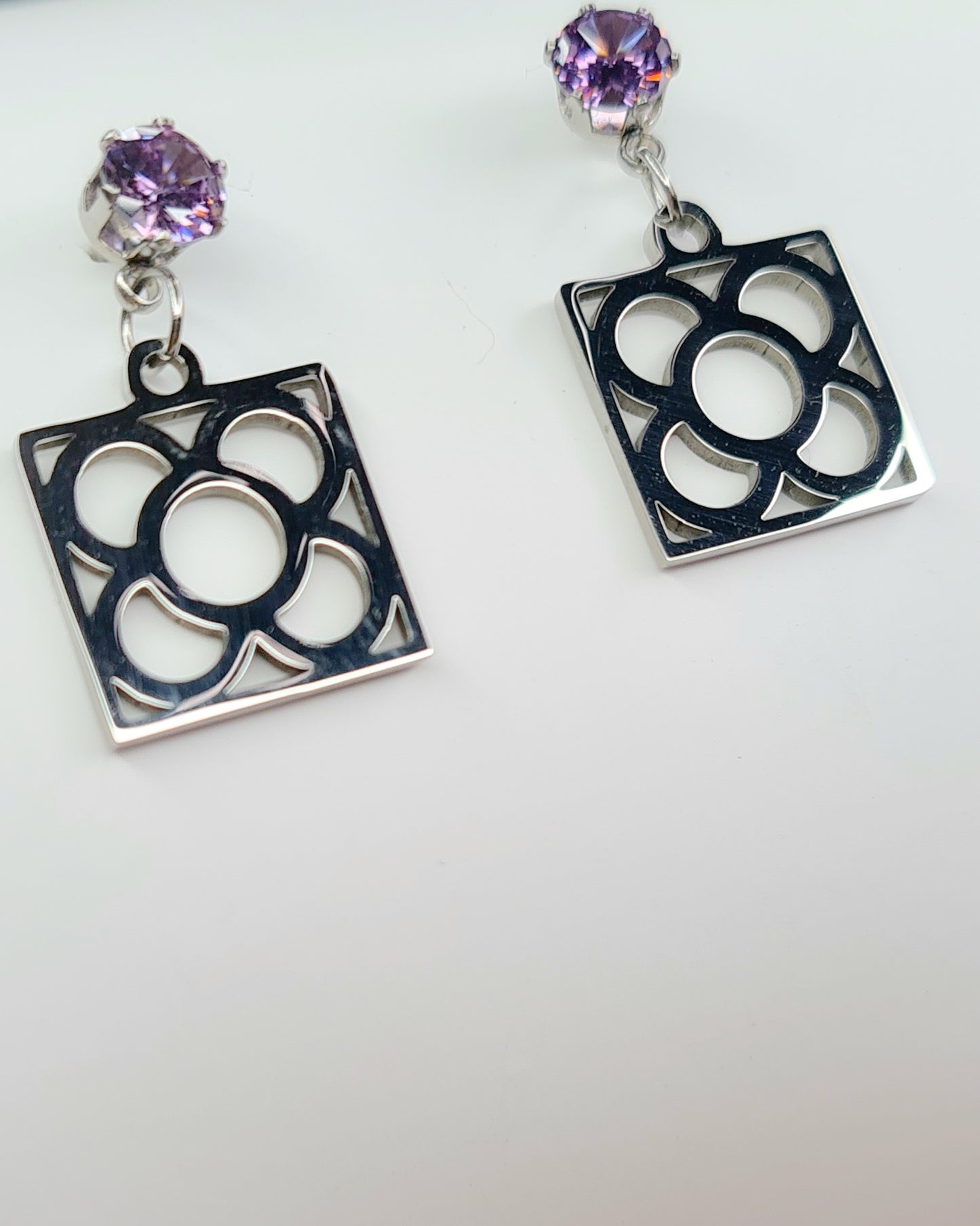 Pendientes de acero inoxidable plateado con tope de circonita lila y la Flor de Barcelona para mujer.