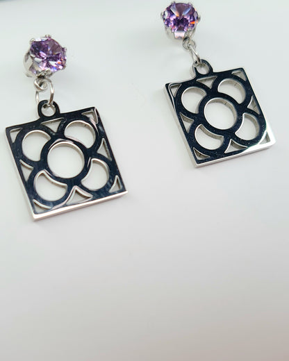 Pendientes de acero inoxidable plateado con tope de circonita lila y la Flor de Barcelona para mujer.