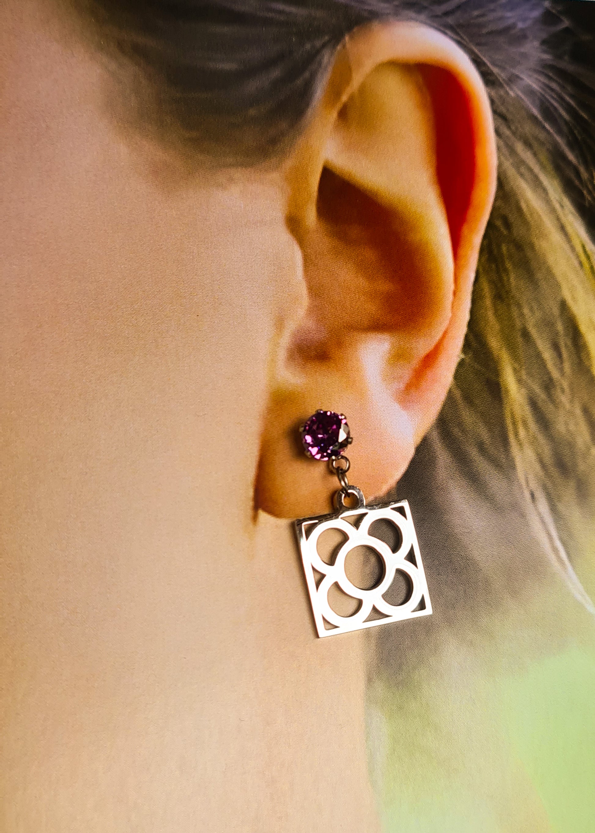 Pendientes de acero inoxidable plateado con tope de circonita lila y la Flor de Barcelona para mujer.