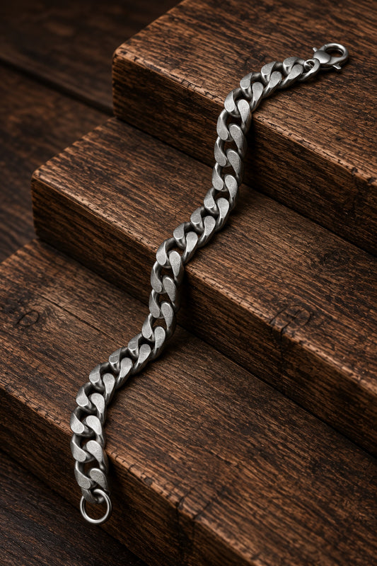 Pulsera de acero inoxidable con acabado mate presentada sobre madera oscura.