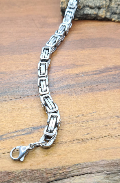 Detalle de pulsera masculina de acero inoxidable sobre madera.