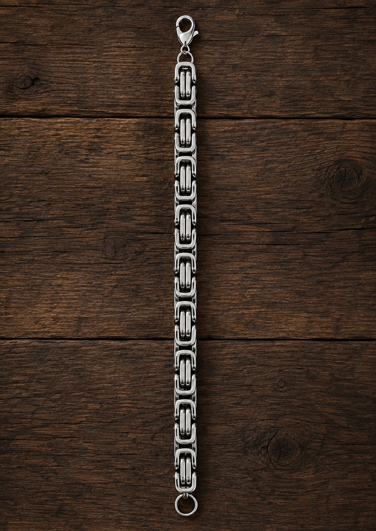Pulsera de acero inoxidable extendida sobre madera oscura.
