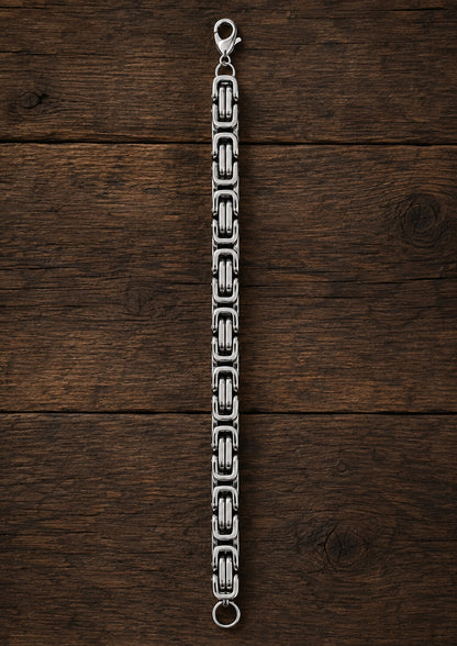 Pulsera de acero inoxidable extendida sobre madera oscura.