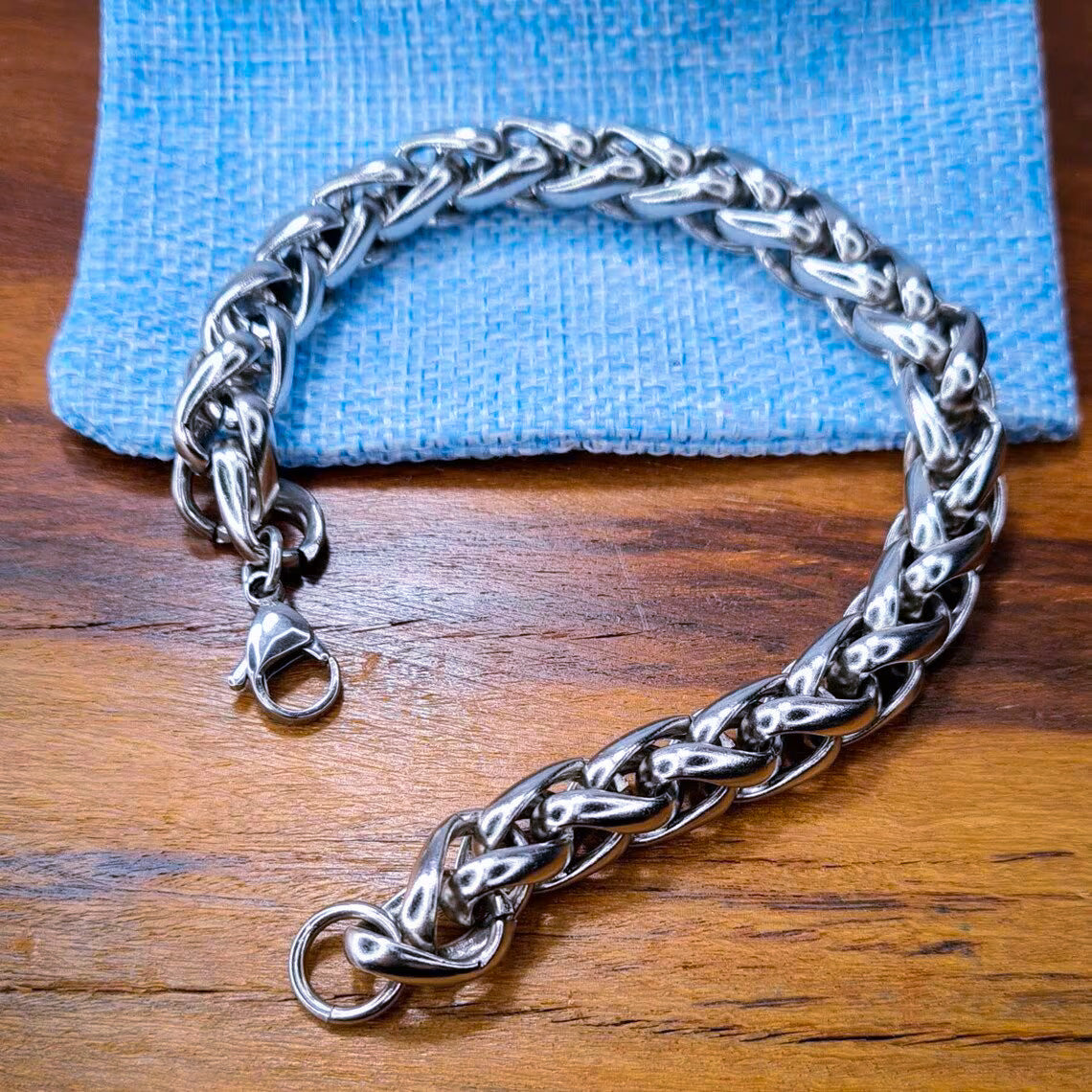 Pulsera acero inoxidable modelo Trenzado, 10mm de ancho. Posa sobre saco de arpillera.