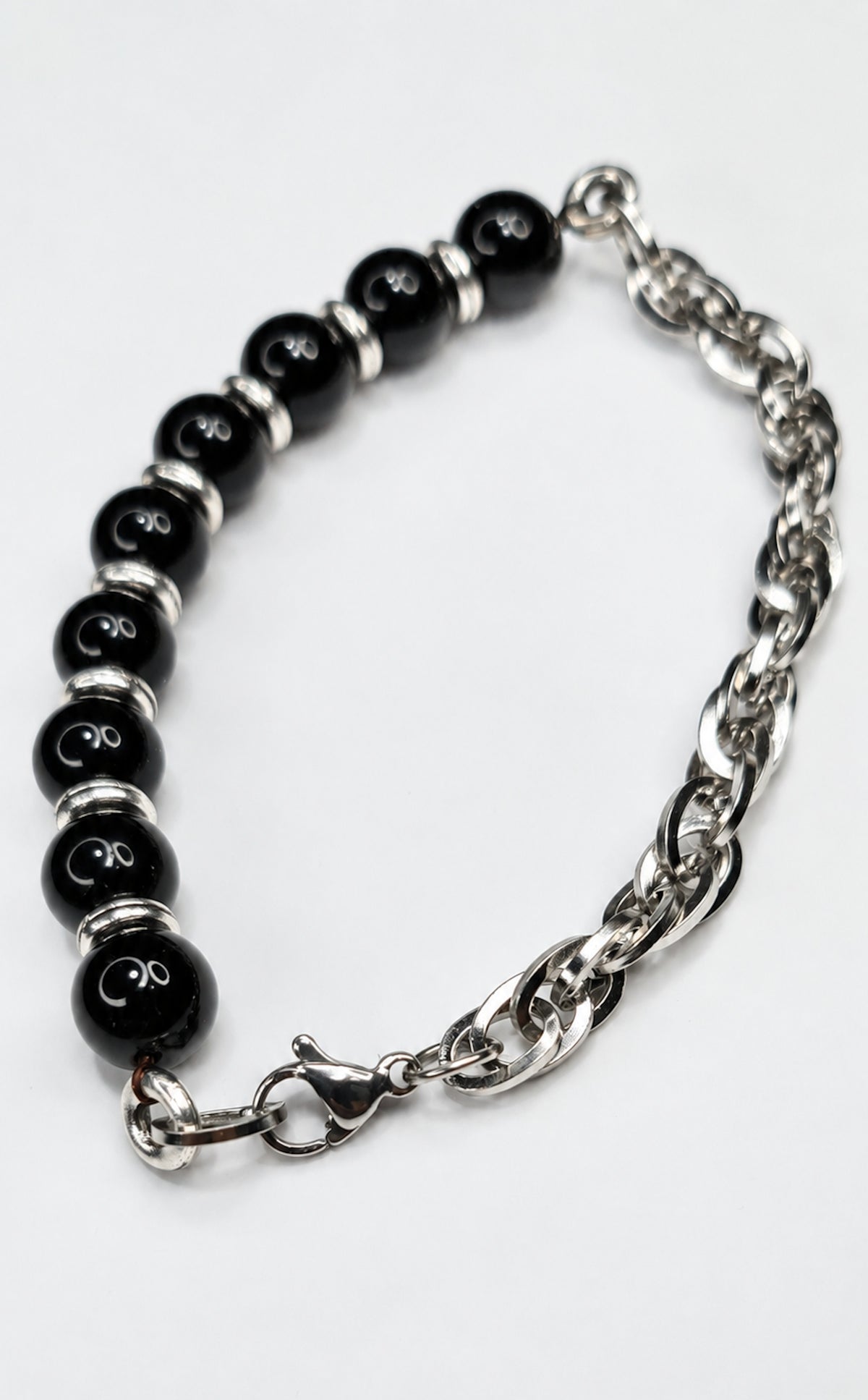 Detalle de pulsera de ónix negro con cadena y cierre metálico.