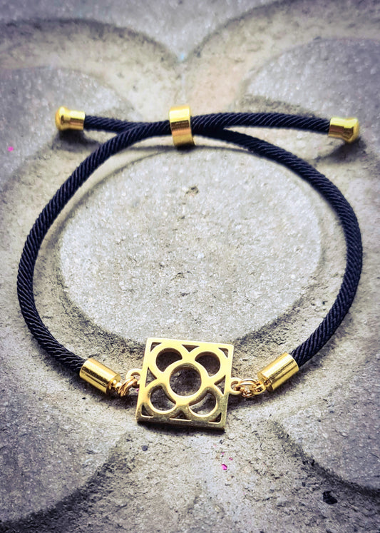Pulsera de algodón negro con la Flor de Barcelona de acero inoxidable dorado, diseño elegante y sencillo.