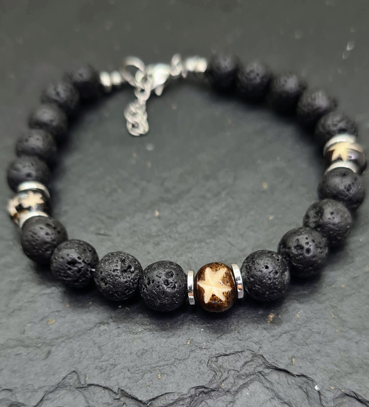 Pulsera masculina de lava volcánica negra con cuentas talladas de hueso de yak y detalles metálicos.