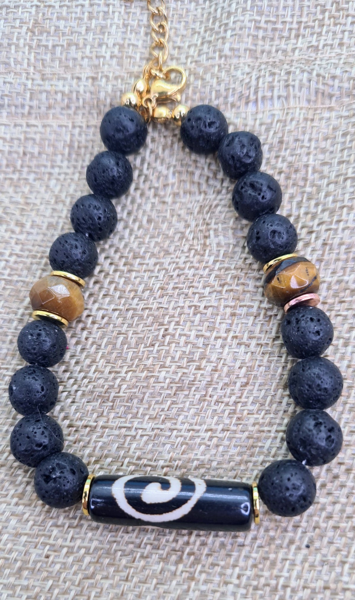 Pulsera completa de lava negra de 6 mm con pieza central alargada de hueso de yak y dos cuentas de ojo de tigre.