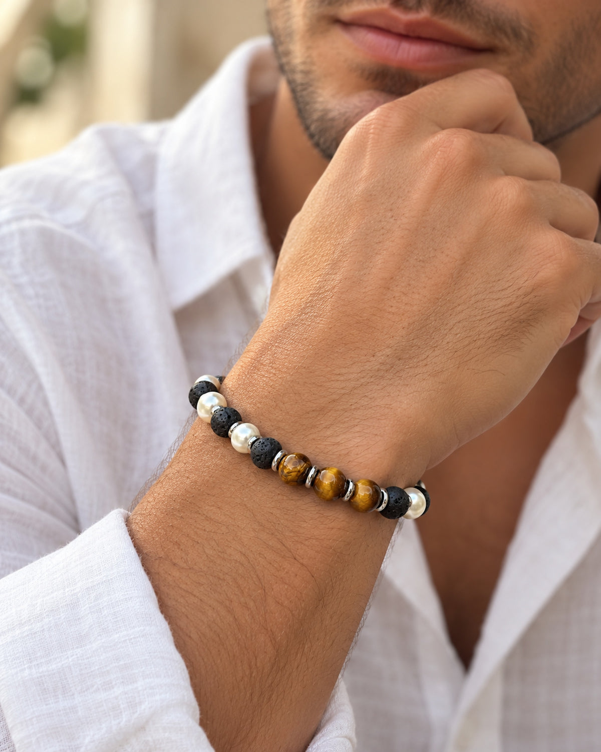Hombre llevando pulsera de lava negra, ojo de tigre y cuentas de perla.