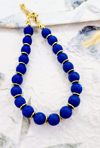 Pulsera de cuentas de lava azul con textura porosa y discos dorados.