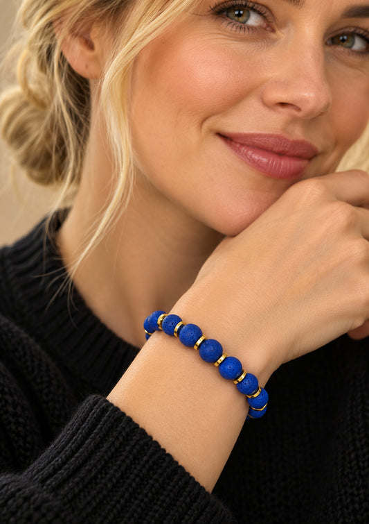 Pulsera de lava azul y detalles dorados puesta en la muñeca.