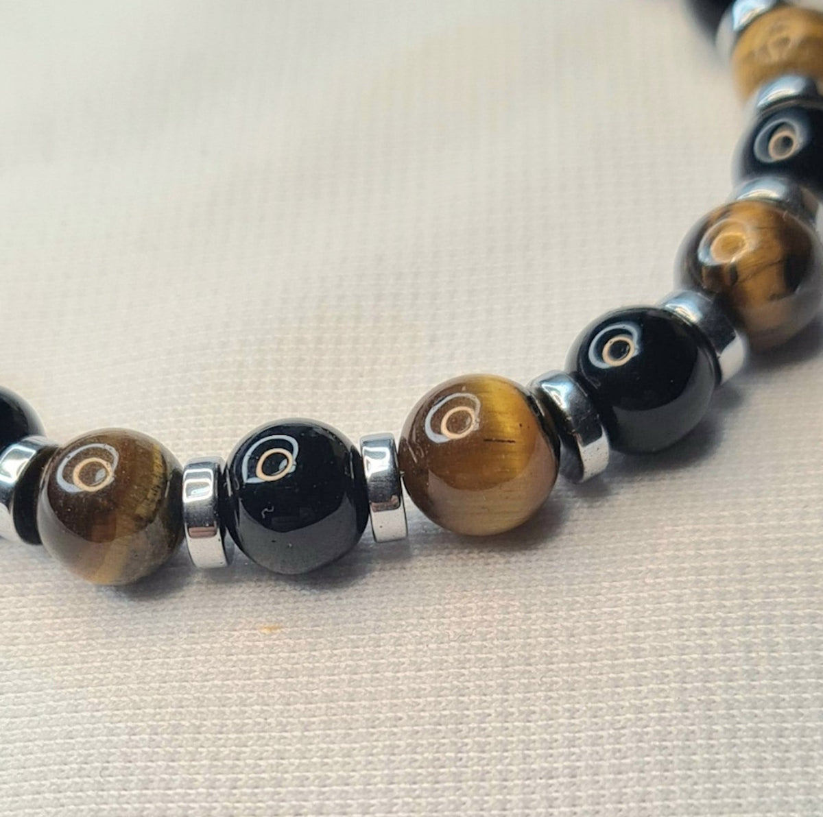 Detalle de cuentas de ónix brillante y ojo de tigre de 6 mm con separadores metálicos.