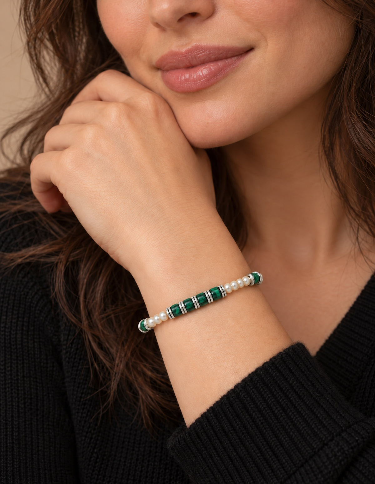 Pulsera de perlas y malaquita llevada en la muñeca.