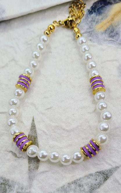 Pulsera completa de perlas blancas con discos de cerámica morados y detalles dorados.