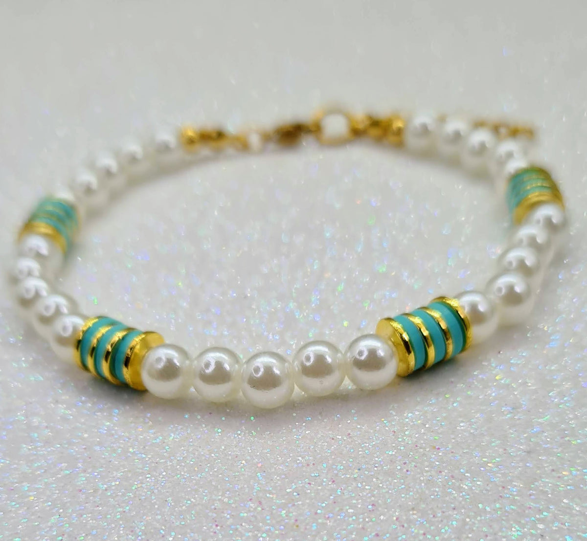 Pulsera de perlas blancas con discos verdes y detalles dorados.