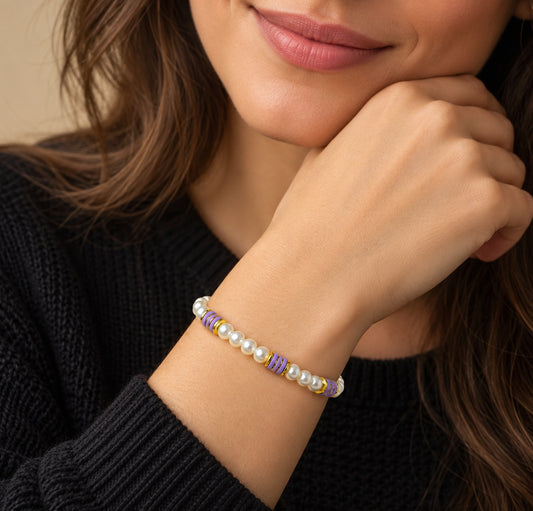 Pulsera de perlas y cerámica morada llevada en la muñeca.