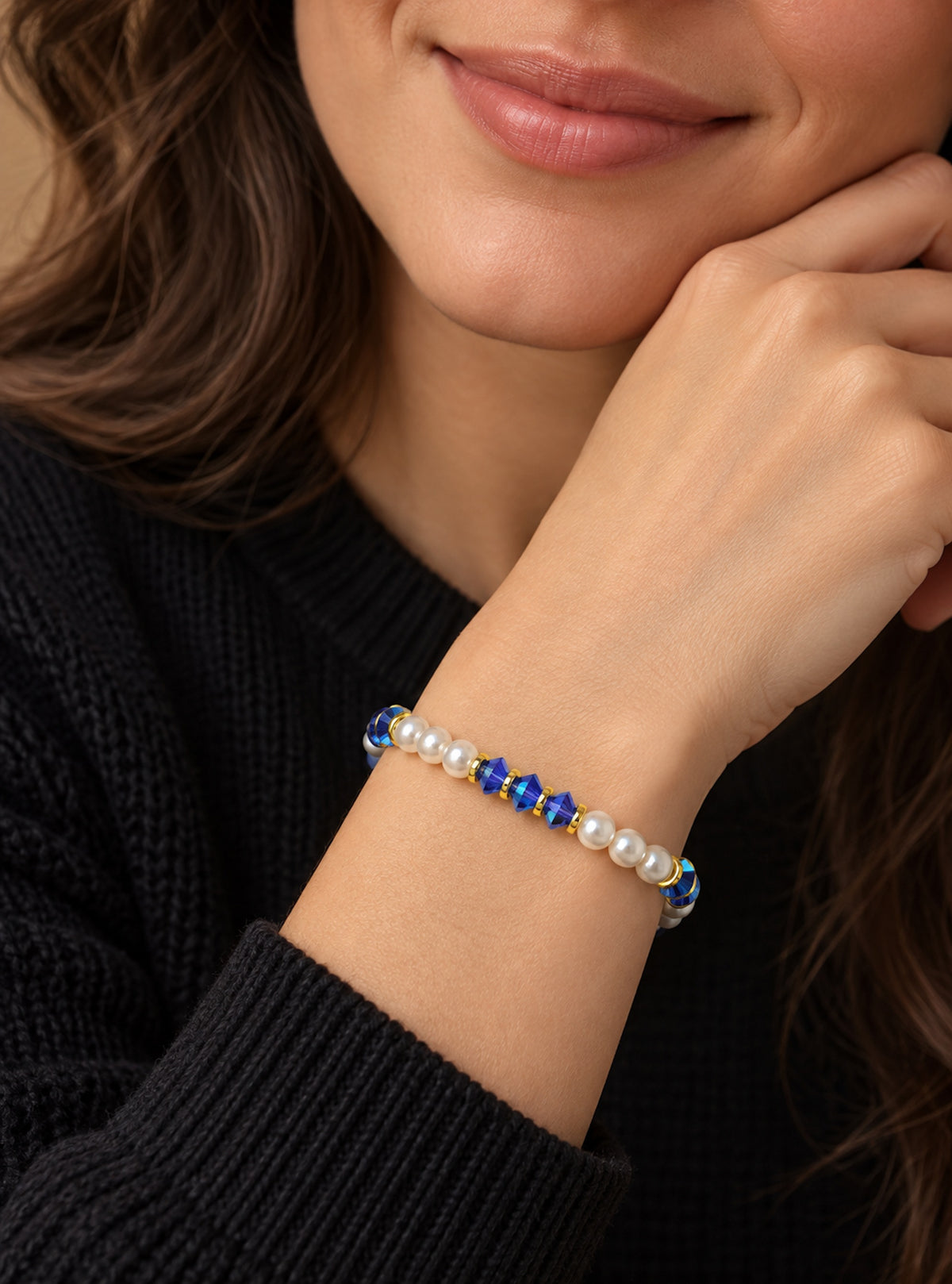 Pulsera de perlas y cristales azules llevada en la muñeca de una mujer.