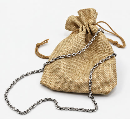 Cadena trenzada de acero presentada junto a una bolsa de tela sobre fondo claro.