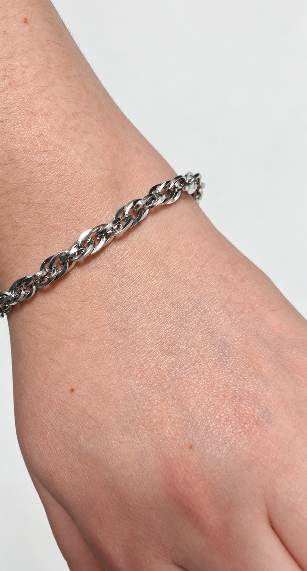 Pulsera de cadena trenzada de acero llevada en la muñeca de una mujer.