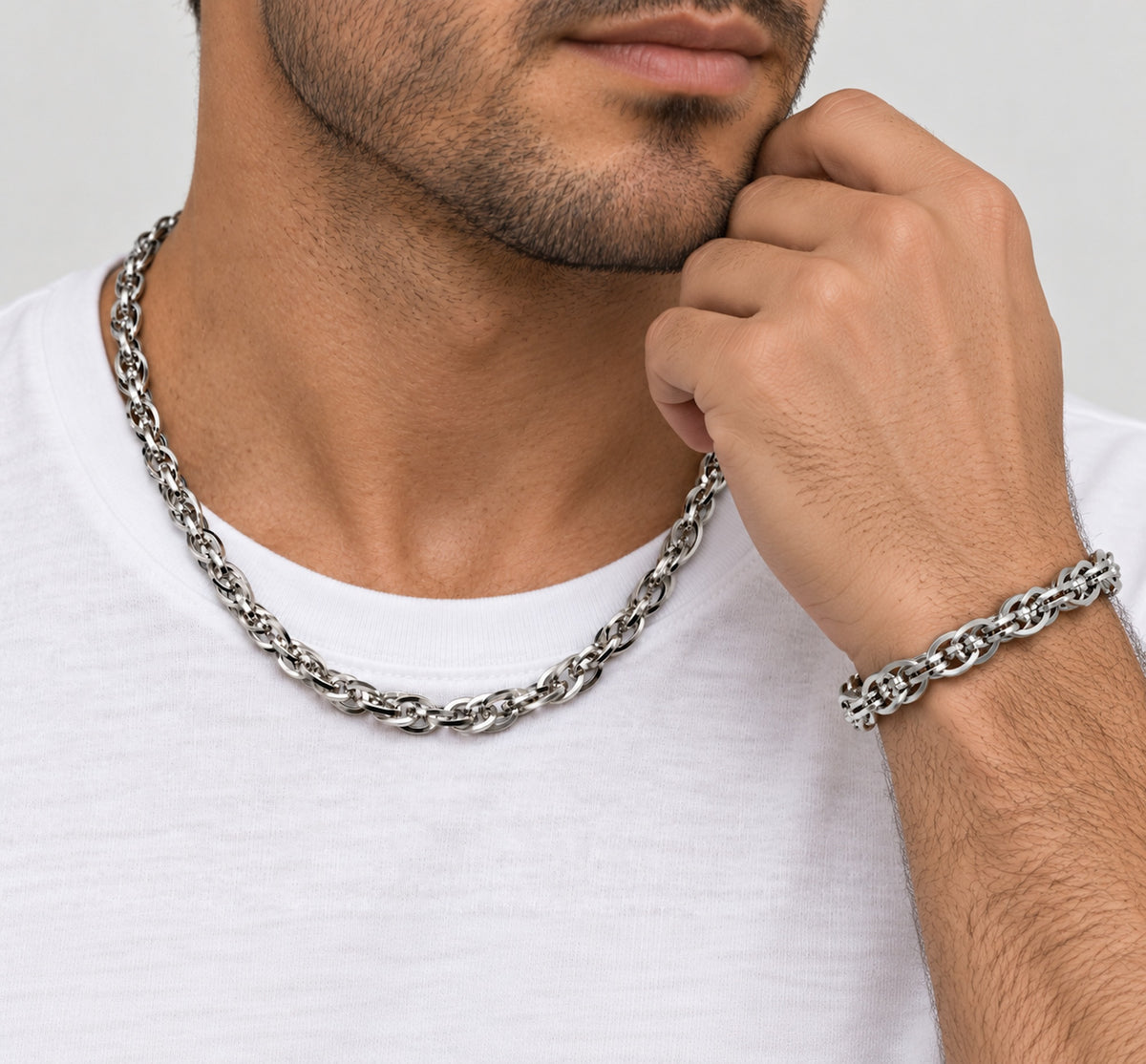 Hombre con cadena trenzada de acero al cuello y pulsera a juego en la muñeca.