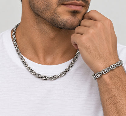 Hombre con cadena trenzada de acero al cuello y pulsera a juego en la muñeca.